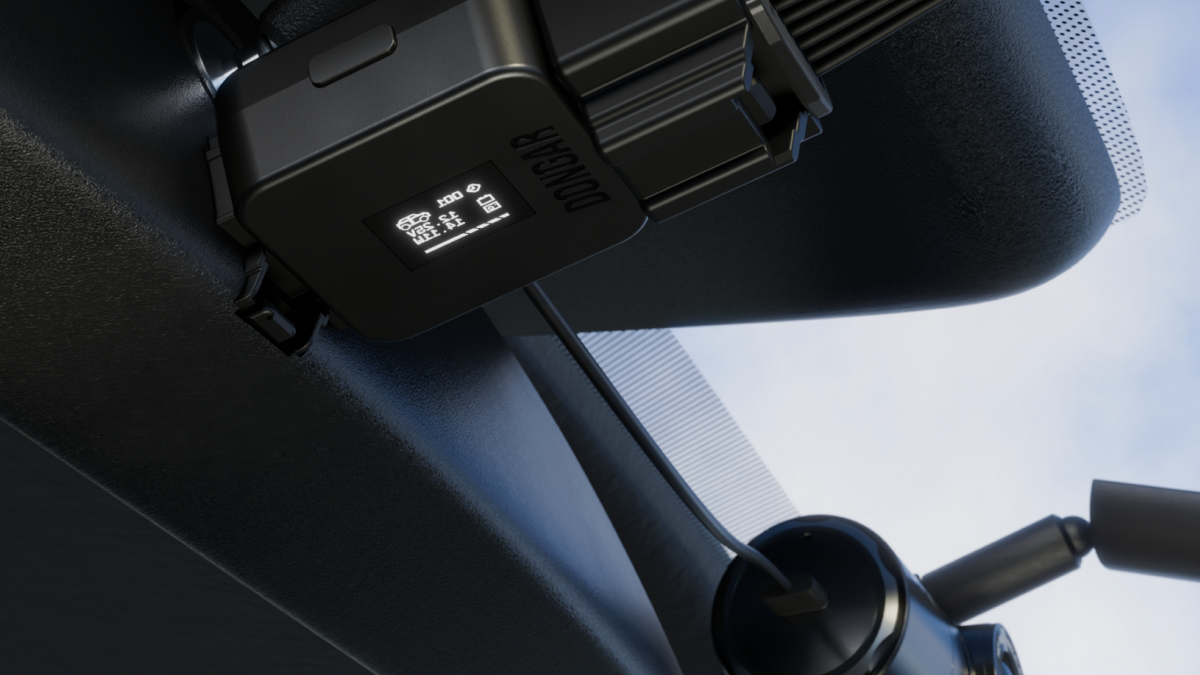 Dongar Compact plugged into the back of a rearview mirror, powering a dash cam